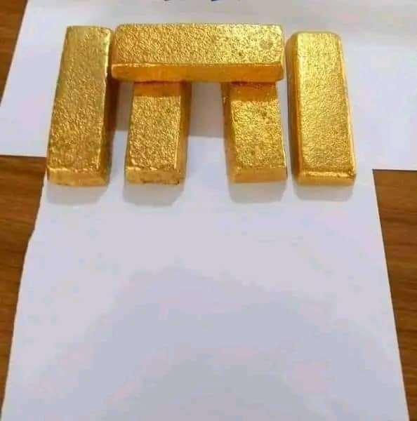 Five cast gold bullion bars arranged on a sheet of white paper