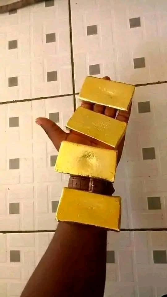 Four cast gold bars balanced along a buyer’s hand and forearm
